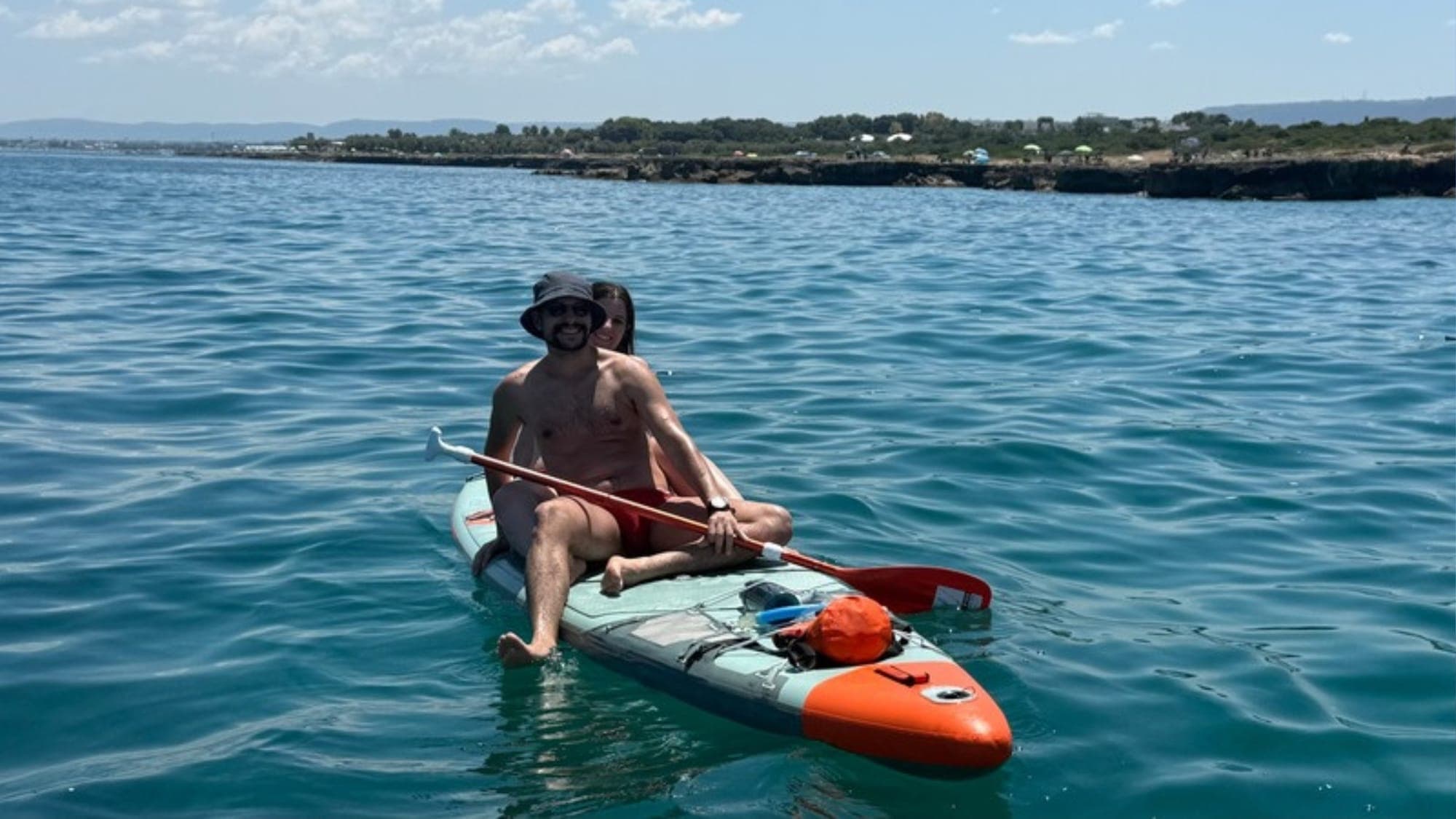 In due su una tavola in mare, lungo la costa