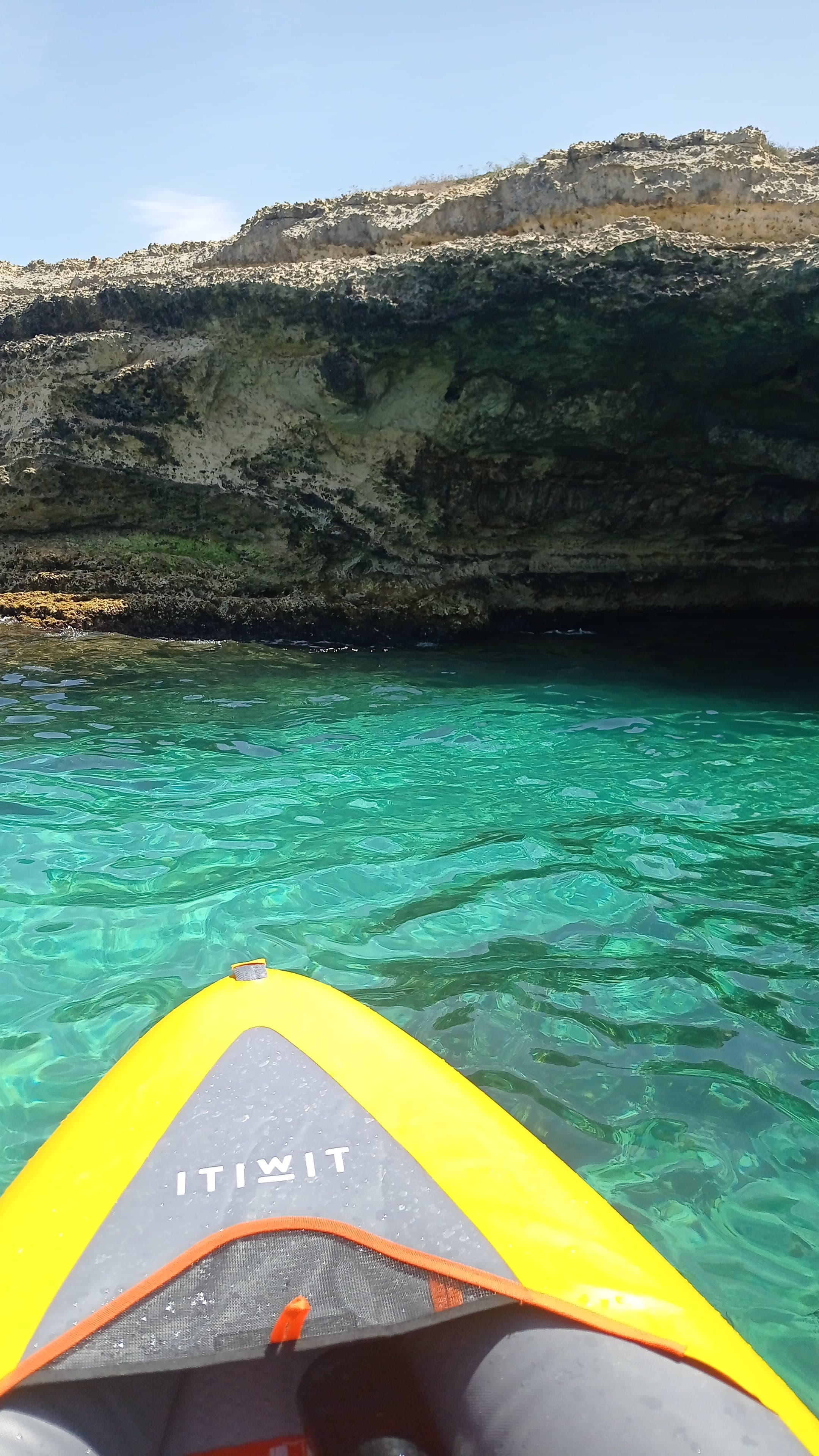 Vista in prima persona da un SUP sull'acqua cristallina di una cala pugliese